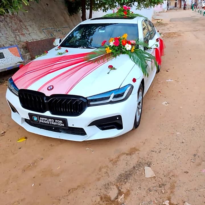 White BMW decorated with red ribbon and flowers
